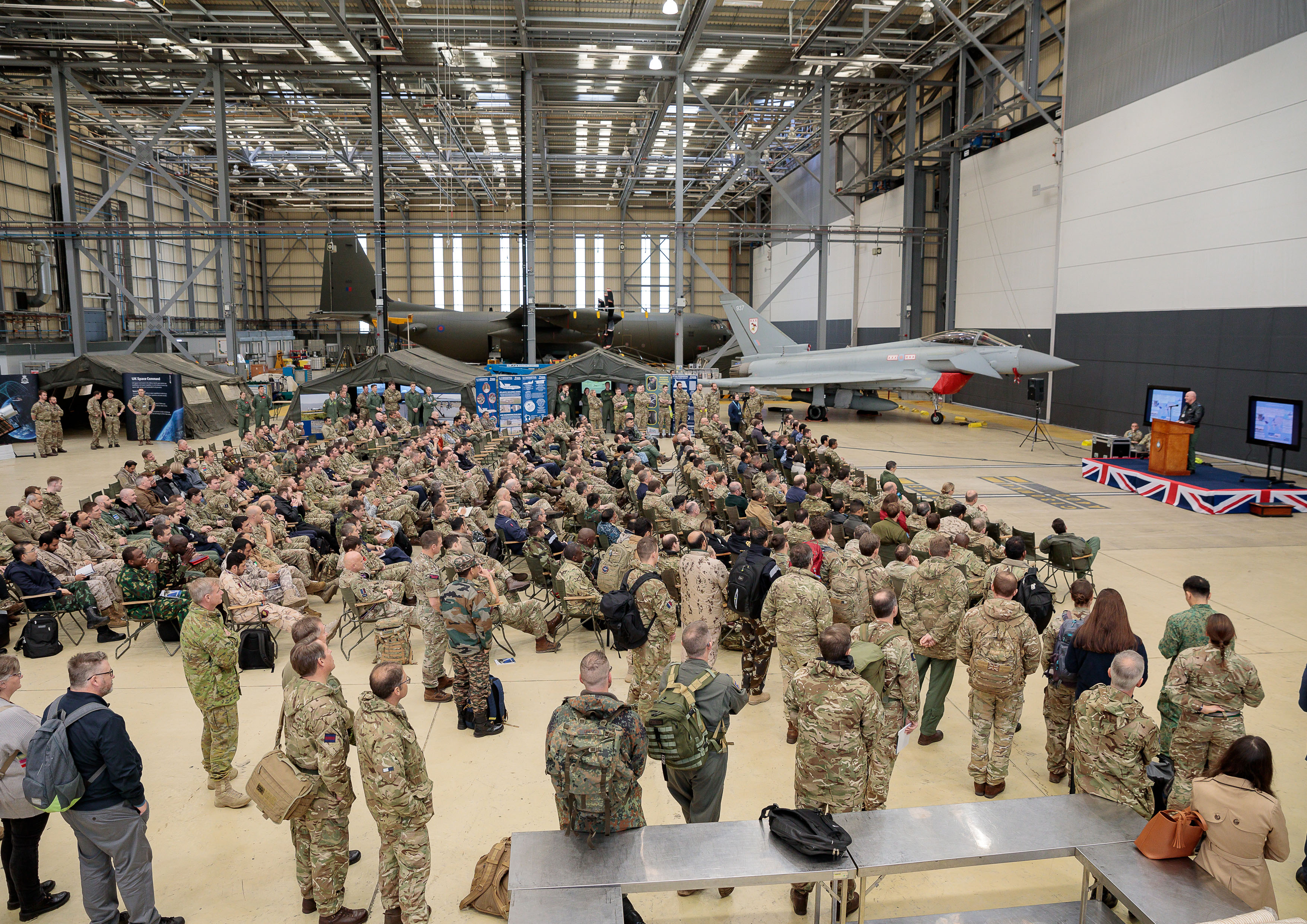 Image shows RAF aviators inside a hangar with stationary aircraft.